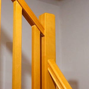 Rohové schody z masívneho dreva s robustným stredovým pilierom, ktorý fixuje zábradlie
